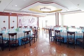 A spacious dining area with round tables, chairs, and a large mural on the wall. - Huanyu Grand Hotel (Yishui Dongfang Shopping Center Chang'an South Road) (Yishui)