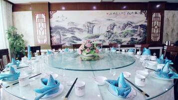 A round table set for dining with a floral centerpiece, surrounded by chairs.