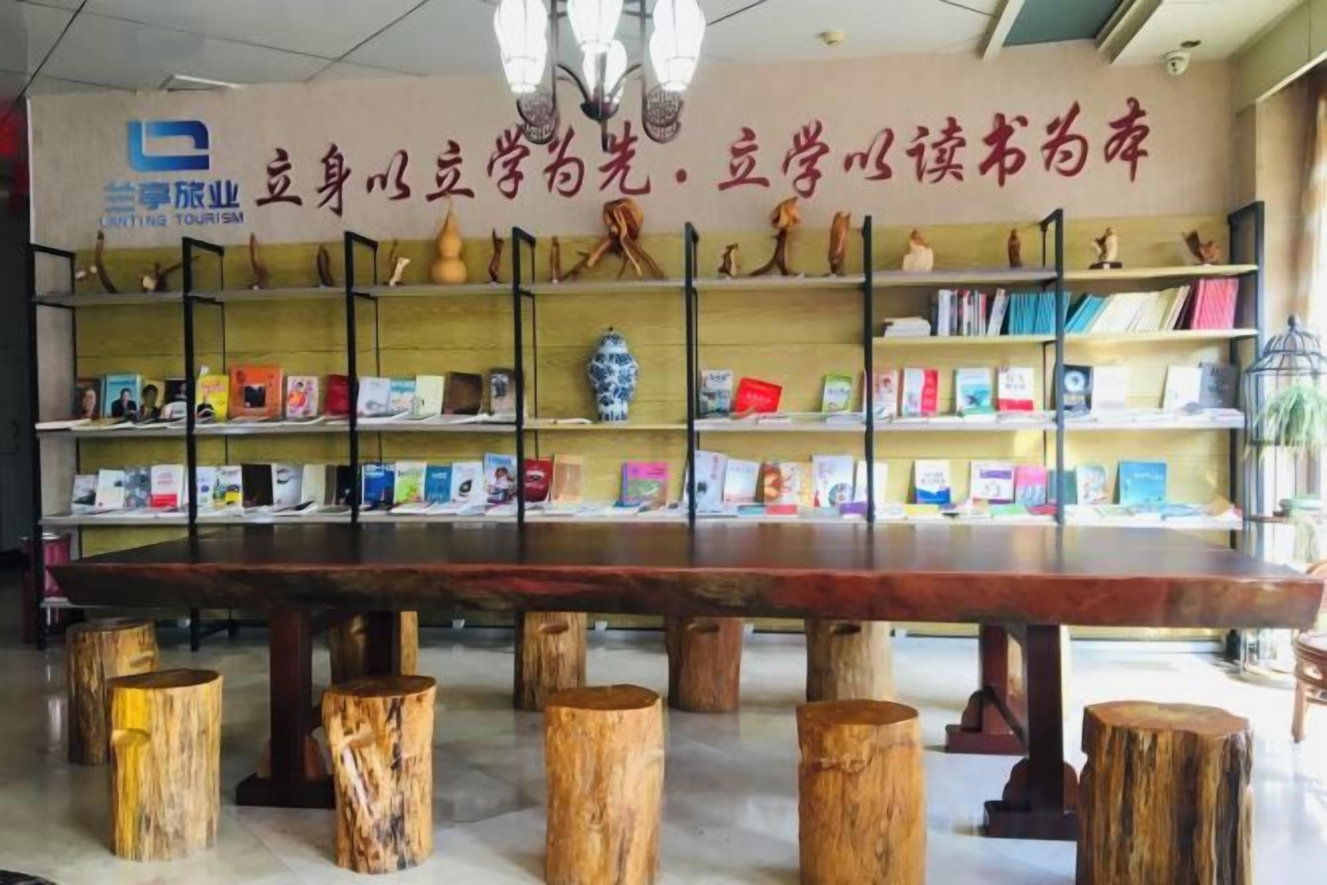 Una librería con una larga mesa de madera rodeada de estanterías repletas de libros.