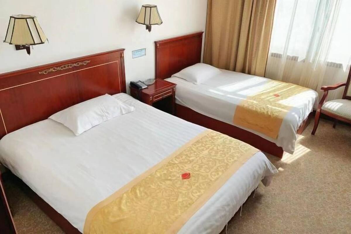 Une chambre d’hôtel avec deux lits, une tête de lit en bois, une table de chevet, une lampe et une chaise.