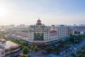 A multi-story building with a prominent red dome, surrounded by trees and a busy street. - Huanyu Grand Hotel (Yishui Dongfang Shopping Center Chang'an South Road) (Yishui)
