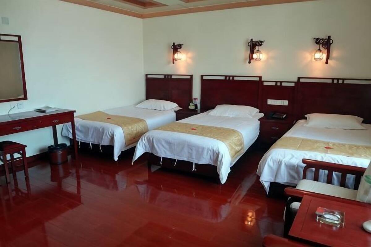 Une chambre d’hôtel avec trois lits, un bureau et une chaise.
