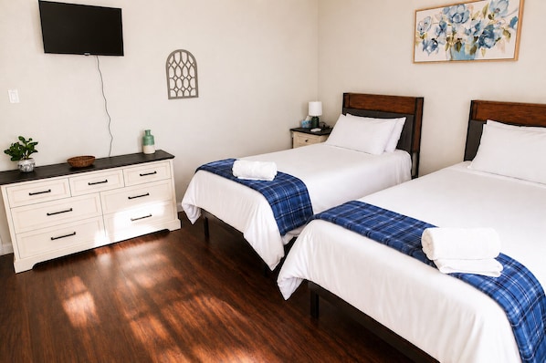 A hotel room with two beds, a dresser, a television mounted on the wall, and a painting. - Family Fun, Movie Theater • Games • Full Kitchen • Quiet Cul-de-Sac SUPERHOST (Farmington)
