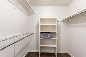 Un armario vestidor con estanterías blancas y barras metálicas para colgar ropa.
