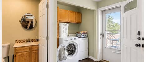 Washer and dryer with light wood cabinets, near a private deck.