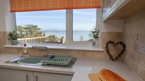 A kitchen with a view of the sea, a heart-shaped decoration, and a loaf of bread on the counter. - Gweld y Mor, Saundersfoot (Saundersfoot)