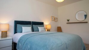 A bedroom with a bed, bedside lamps, a wall-mounted mirror, and a hanging light fixture. - Gweld y Mor, Saundersfoot (Saundersfoot)
