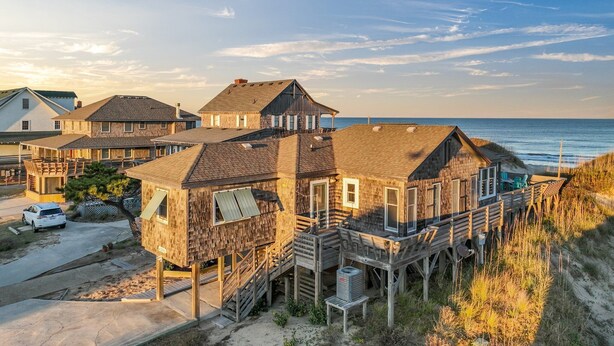 A beachfront house with multiple levels, a wooden deck, and a view of the ocean. - 'Loophole' | Oceanfront | Historic Cottage (Nags Head)