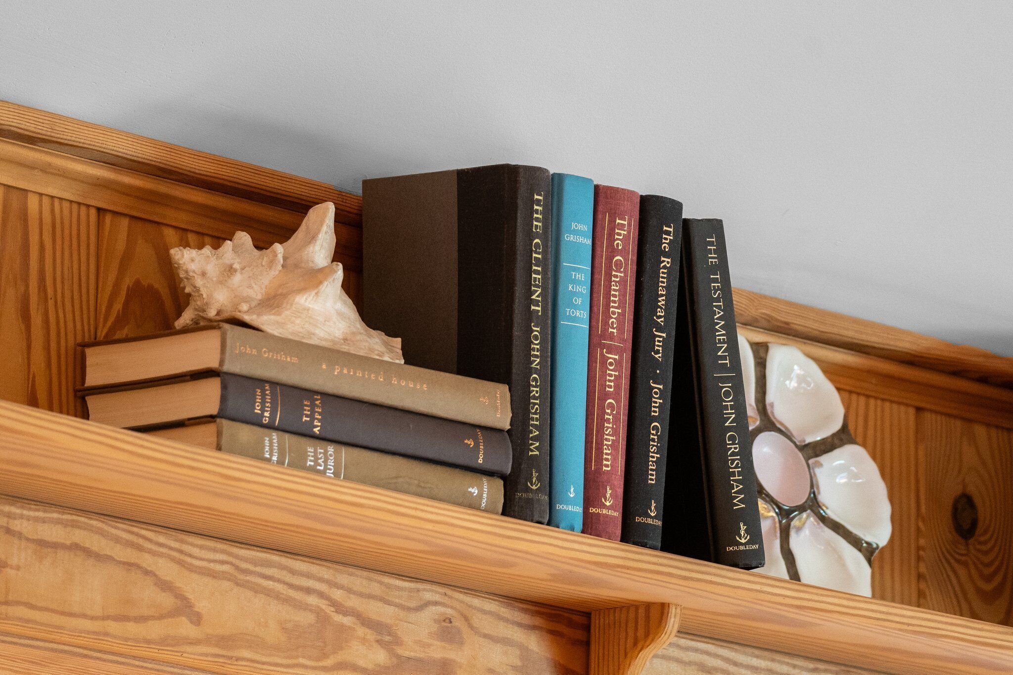 Une bibliothèque en bois avec plusieurs livres et un coquillage.