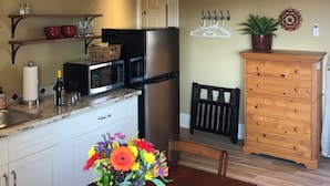 A compact kitchen with a refrigerator, microwave, and a wooden cabinet.