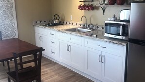 A kitchen with white cabinets, a stainless steel refrigerator, a microwave, and a sink.