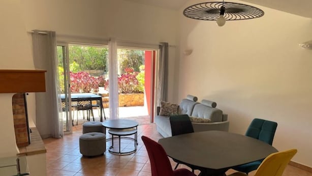 A dining area with a round table, red and yellow chairs, and a ceiling fan.