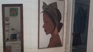 Un pasillo con pared blanca de paneles, un retrato enmarcado y una puerta con panel de vidrio satinado.