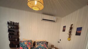 Un dormitorio con cama, lámpara colgante, aire acondicionado y adornos en la pared.