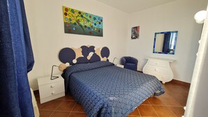A bedroom with a bed, a nightstand, a dresser, a chair, a painting, and a mirror.