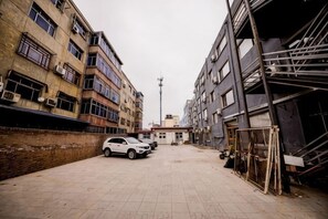 Eine schmale Stadtstraße mit Gebäuden an beiden Seiten, einem stehenden Auto und Baumaterialien.