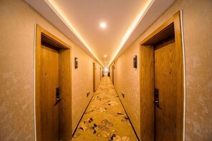 A hotel hallway with wooden doors, carpeted flooring, and recessed lighting. - Ximan Collection Hotel (Bazhou Pedestrian Street) (Bazhou)