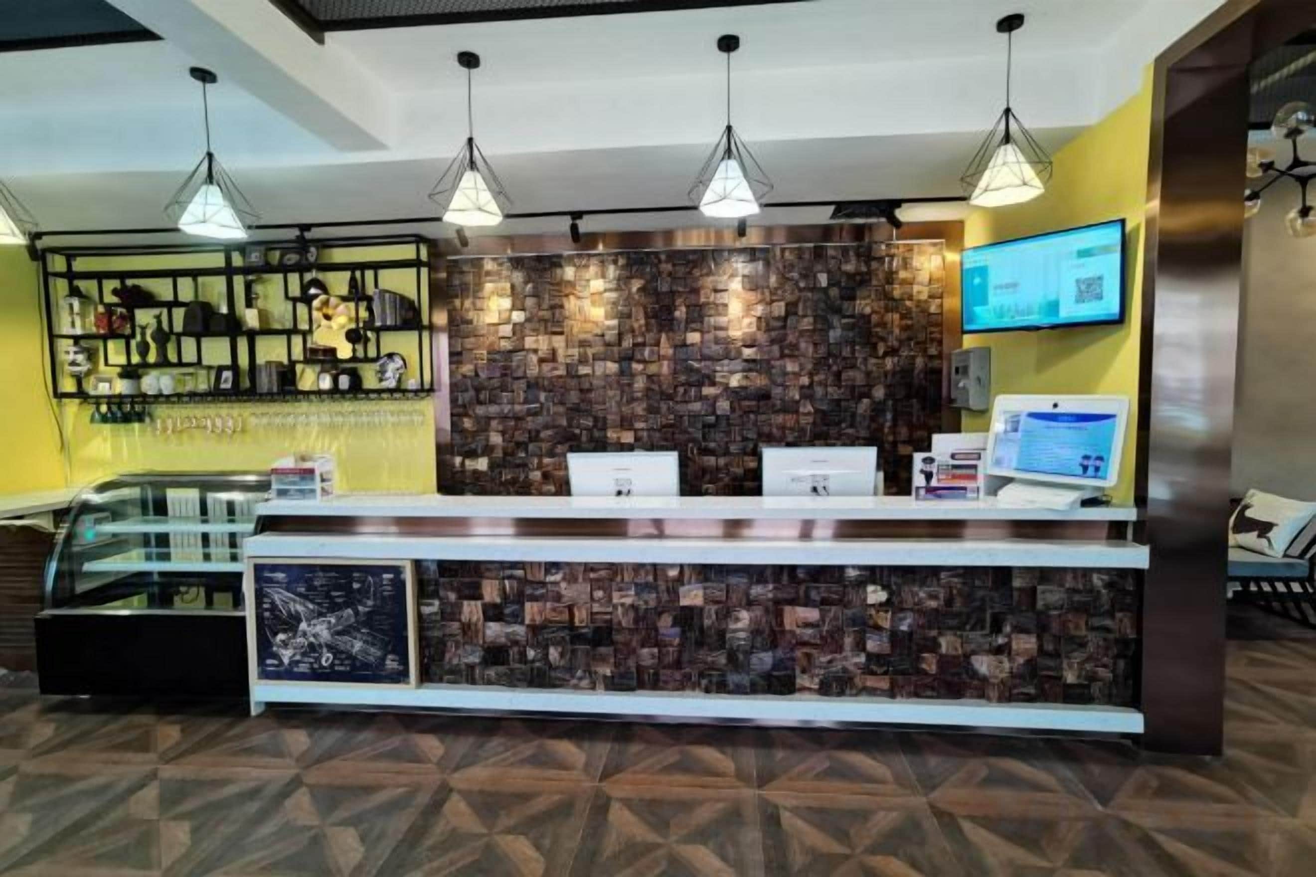 A reception area with a counter, a digital screen, and a wall with a patterned design.