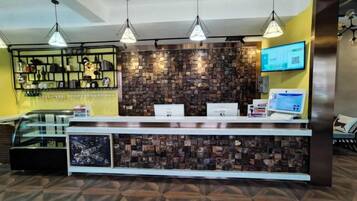 A reception area with a counter, a digital screen, and a wall with a patterned design.