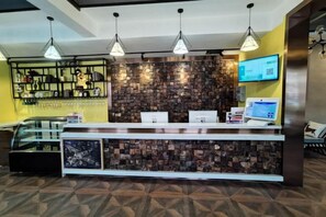 Un área de recepción con mostrador, una pantalla digital y un muro con diseño decorativo.