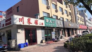 A building with multiple storefronts, including a restaurant and a shop with a green sign.