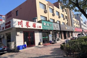 Um edifício com várias lojas, incluindo um restaurante e uma loja com uma placa verde.