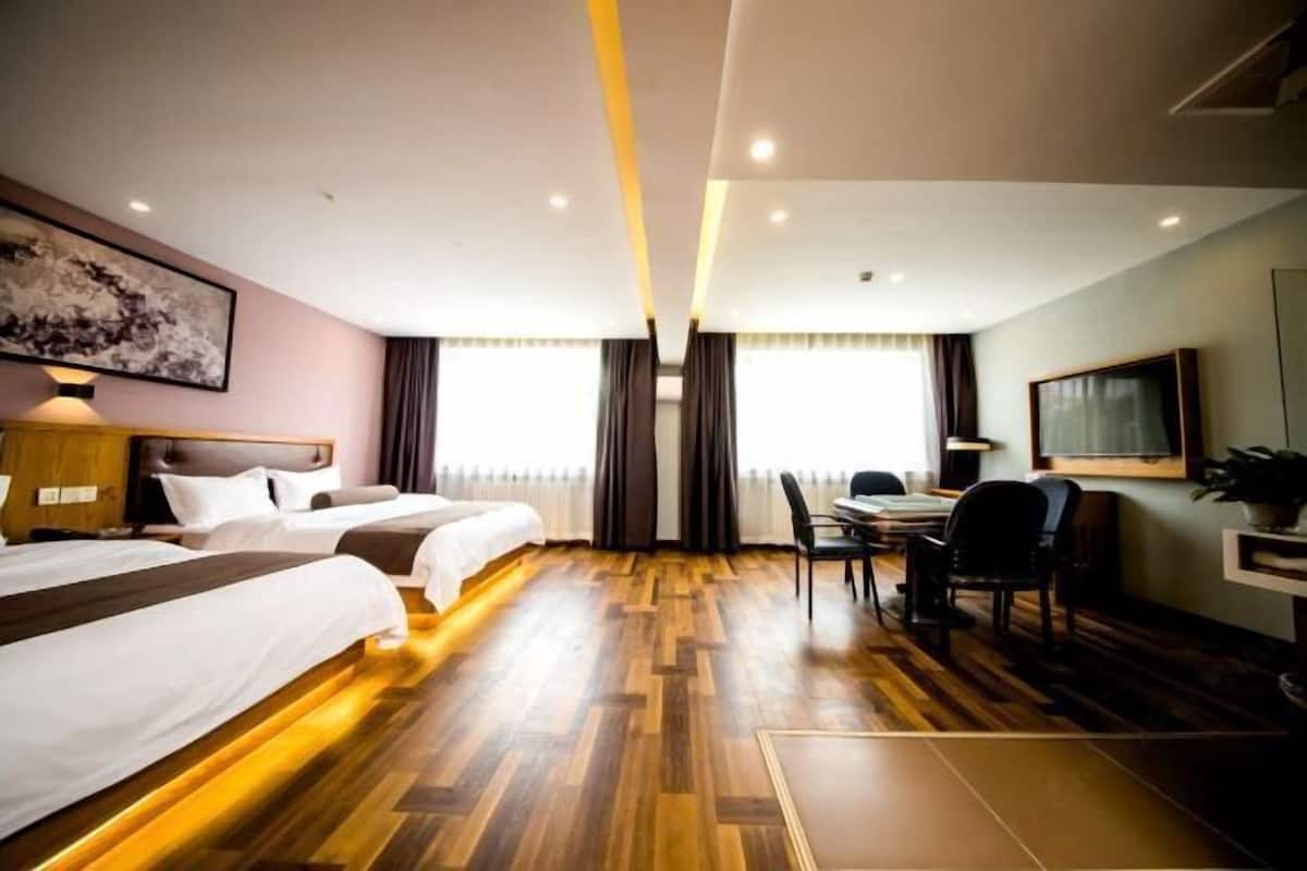 A hotel room with two beds, a desk, a chair, a TV, and a large window.
