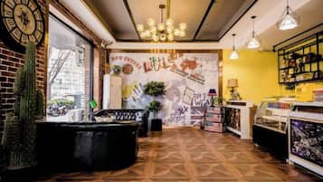 A cafe interior with a brick wall, a black sofa, a mural, and a coffee machine.