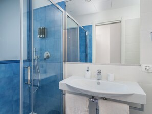 A modern bathroom with a glass shower enclosure, a white sink, and a large mirror. - De Vivo Realty - Pusisò Sorrento (Sorrento)