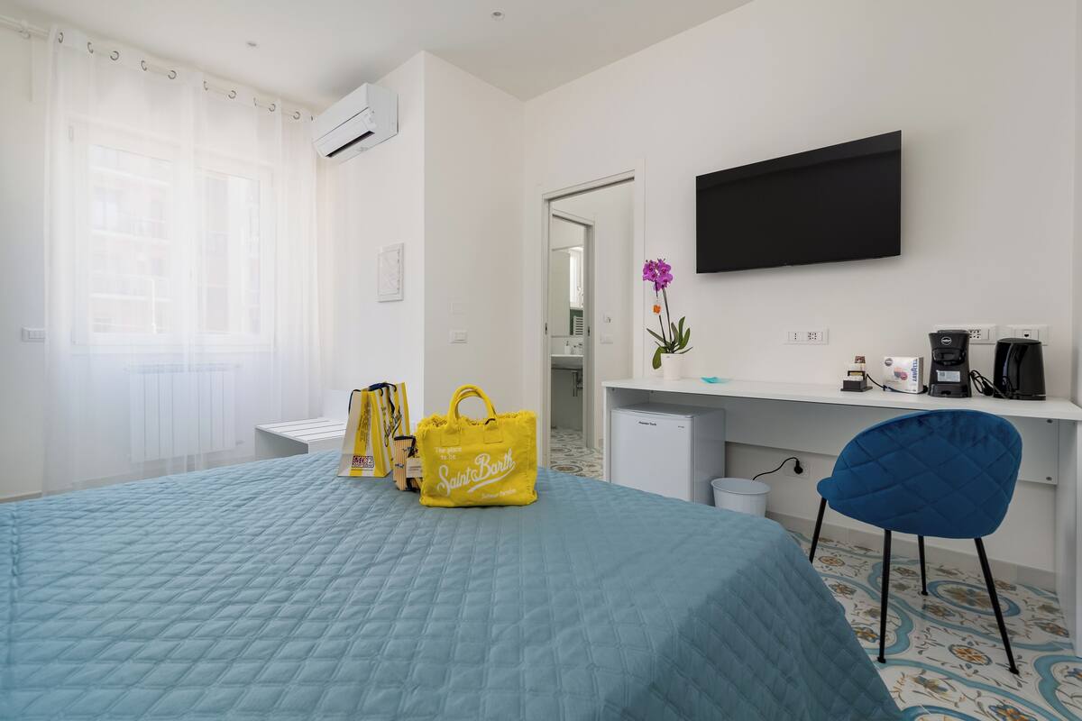 Une chambre d’hôtel équipée d’un lit, d’un bureau, d’une chaise, d’une télévision et d’un petit réfrigérateur.
