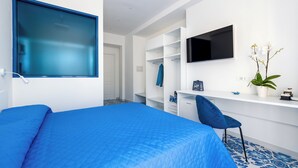 Un dormitorio moderno con una cama grande, un escritorio, una silla y un televisor montado en la pared.