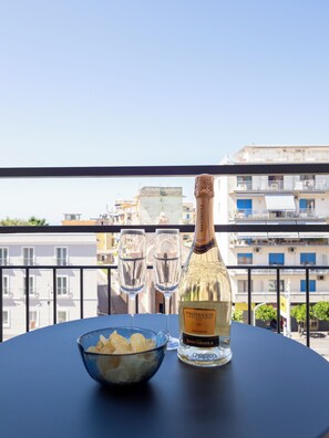 A table with a bottle of Prosecco and two glasses on a balcony overlooking a cityscape. - De Vivo Realty - Pusisò Sorrento (Sorrento)