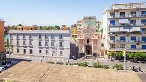 Un edificio de varios pisos con balcones, una entrada central de arquitectura ornamentada y un cielo despejado.