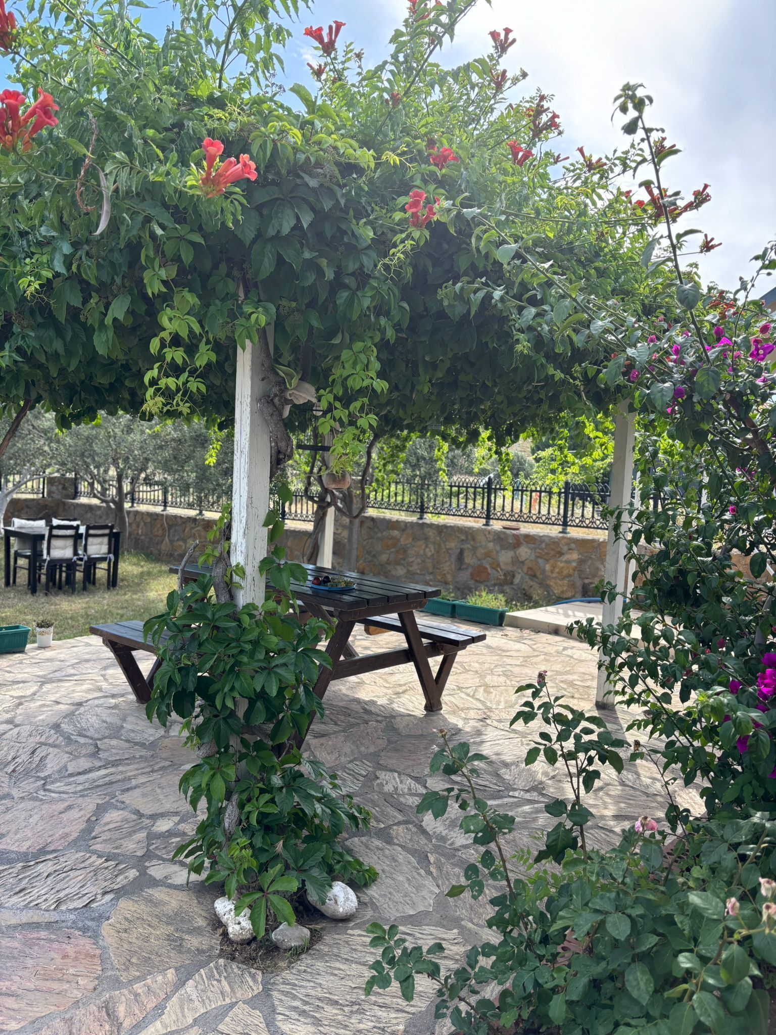 An outdoor patio area with stone flooring, a wooden table, and chairs.