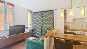 A modern living room with a TV, sofa, and dining area. - N&J - REFLET D'OR - Vieux Nice - Neau beach (Niza)