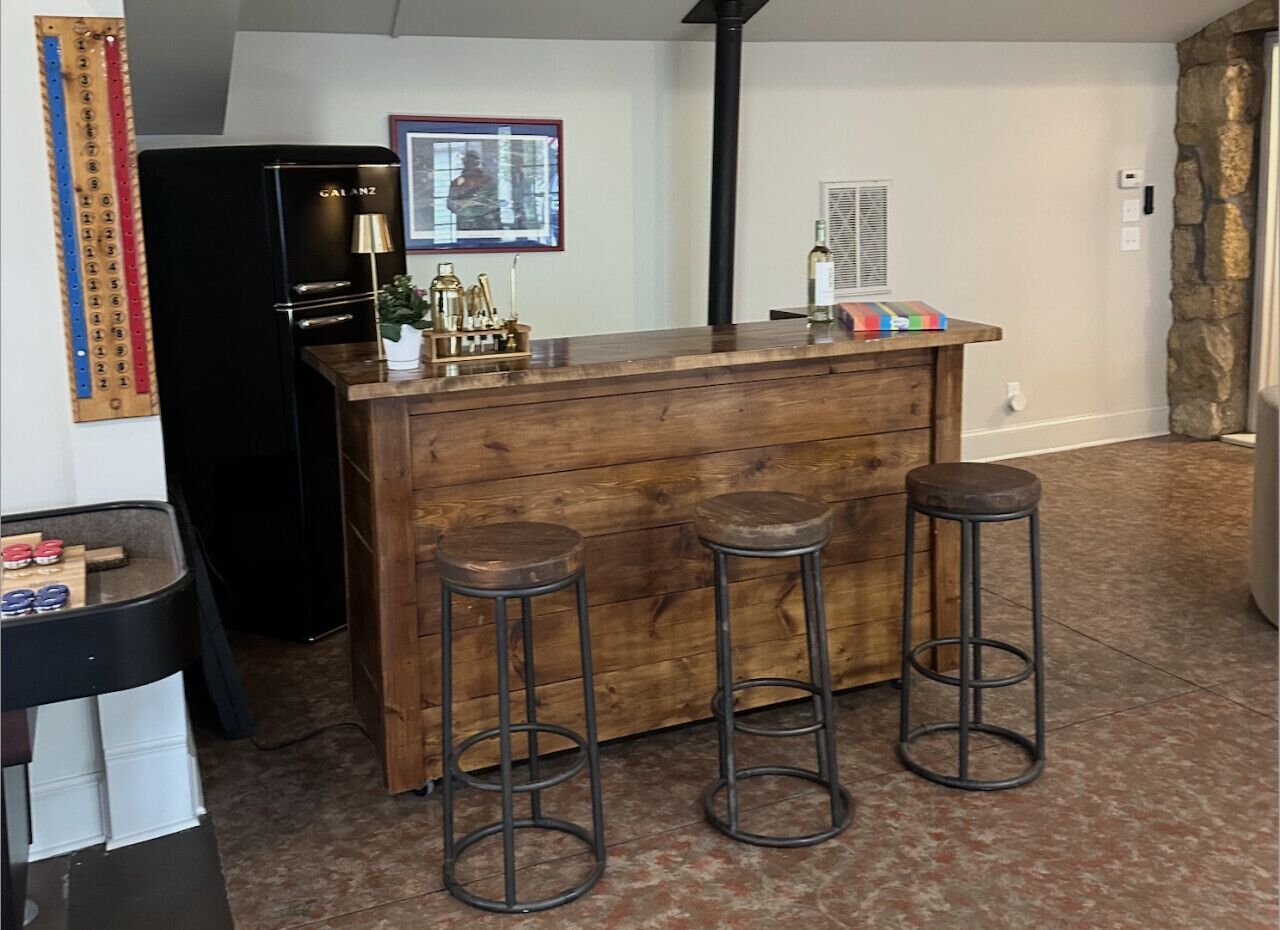 A bar area with a wooden counter and three stools.