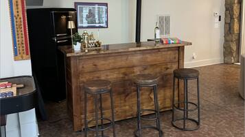 A bar area with a wooden counter and three stools.