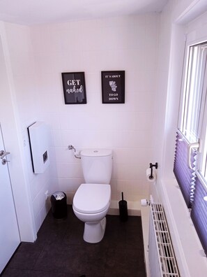 A small, clean bathroom with a white toilet, a trash bin, and two framed signs on the wall. - Farm between the Rheingau and the Taunus (Schlangenbad)
