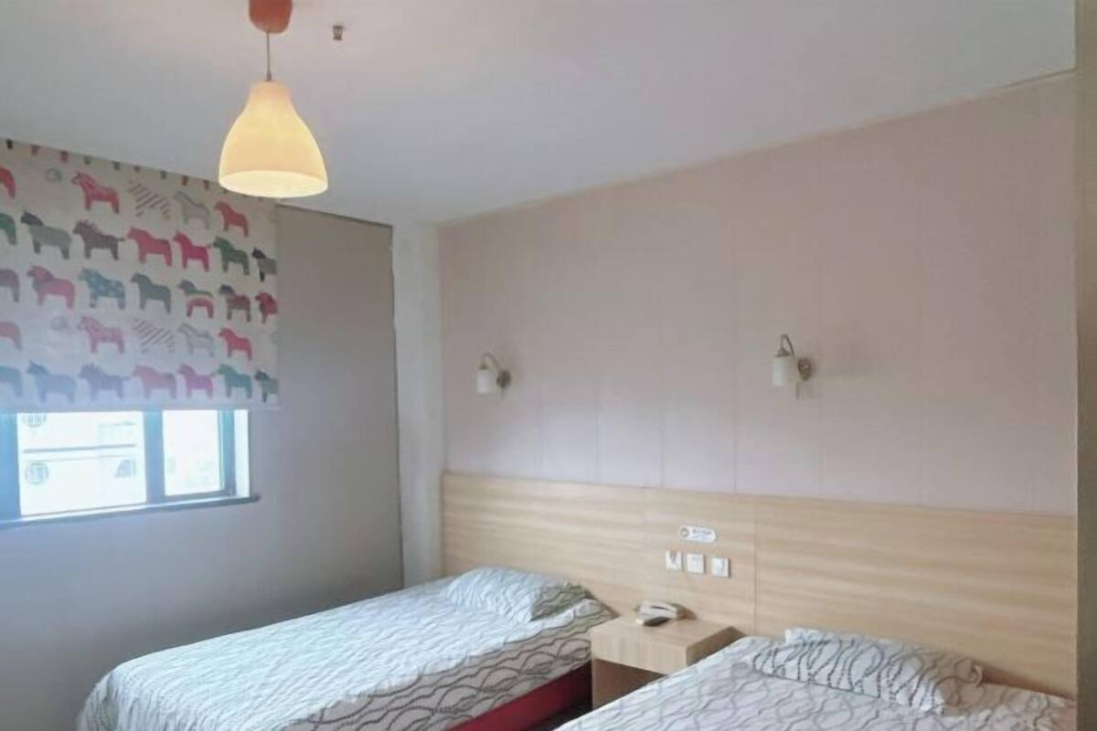 Ett hotellrum med två separata sängar, en sänggavel i trä, ett fönster med utsikt och en vägg med ett hästmönster.
