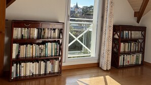 A spacious attic room with wooden beams, a large skylight, and two bookshelves filled with books.