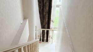A staircase with white balusters and a green carpet leading to a landing. - Beijing Ruistin Hotel (Beijing Daxing New Airport Qingyuan Road Subway Station) (Beijing)