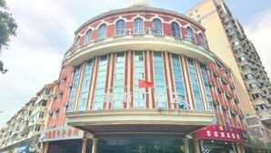 A multi-story building with a curved facade, large windows, and a prominent red flag. - Beijing Ruistin Hotel (Beijing Daxing New Airport Qingyuan Road Subway Station) (Beijing)