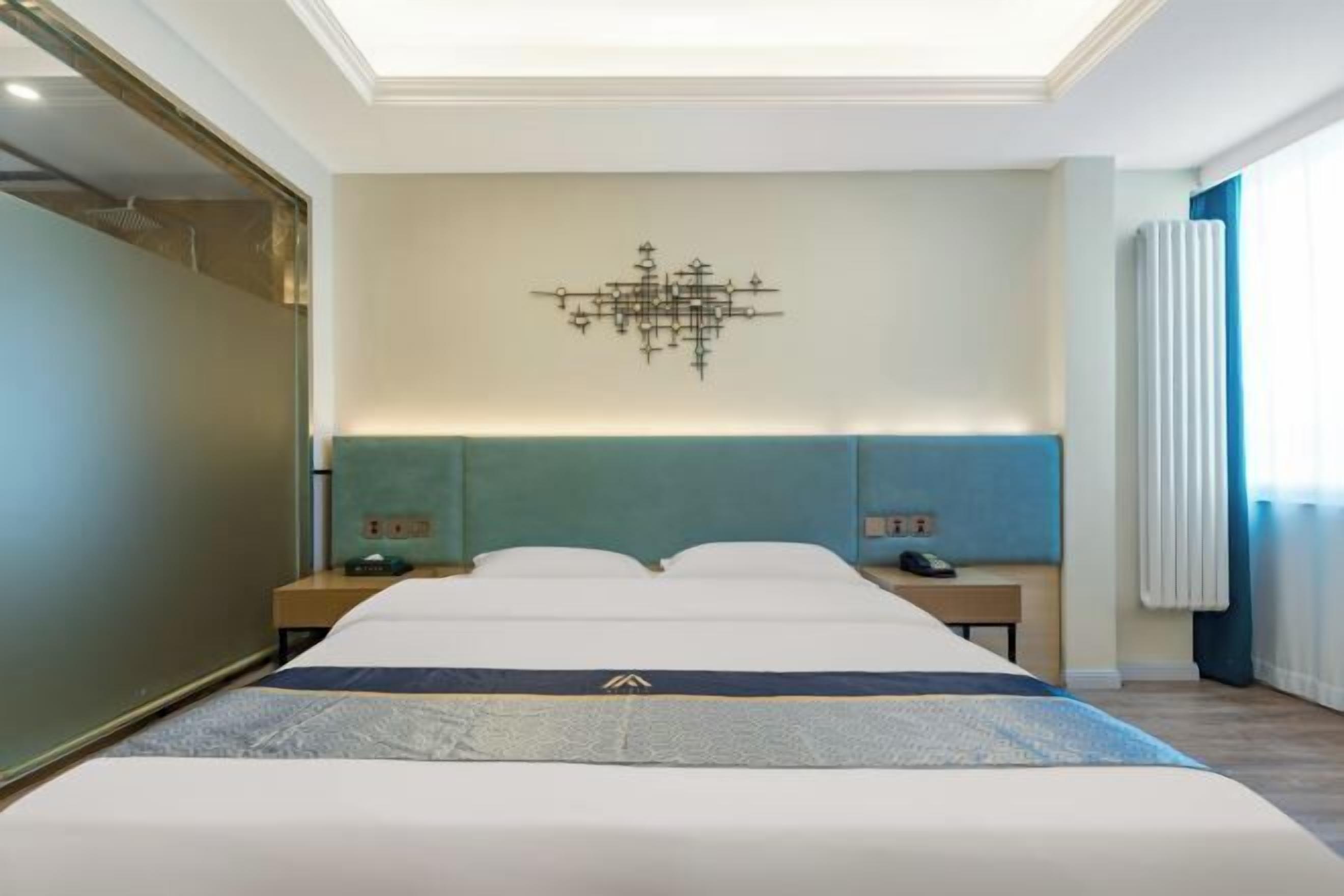 Une chambre d’hôtel avec un grand lit, une œuvre d’art accrochée au mur et une fenêtre avec des rideaux.