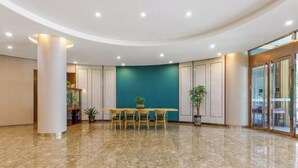 A spacious lobby with a marble floor, a round table with chairs, and a teal accent wall. - Beijing Ruistin Hotel (Beijing Daxing New Airport Qingyuan Road Subway Station) (Beijing)