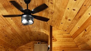Ein gemütliches Blockhauszimmer mit einem Bett, einer Waschmaschine und einem Deckenventilator.