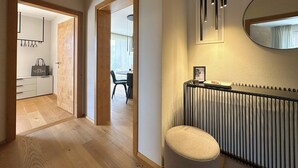 Un interior moderno con piso de madera, una zona de comedor con mesa y sillas, un radiador y un espejo en la pared.