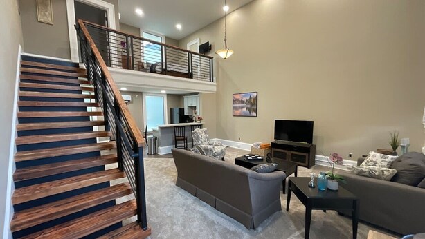Un salon spacieux avec un escalier, un canapé, une table basse et un téléviseur.