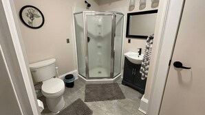 Une salle de bain avec une douche à parois de verre, des toilettes, un lavabo et un miroir.