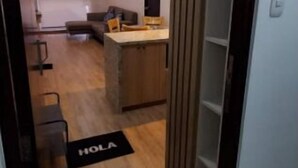 Un pasillo que da a una cocina con mostrador de madera y una zona de comedor.