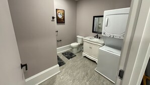 Une petite salle de bain comprenant des toilettes, un lavabo et un lave-linge.